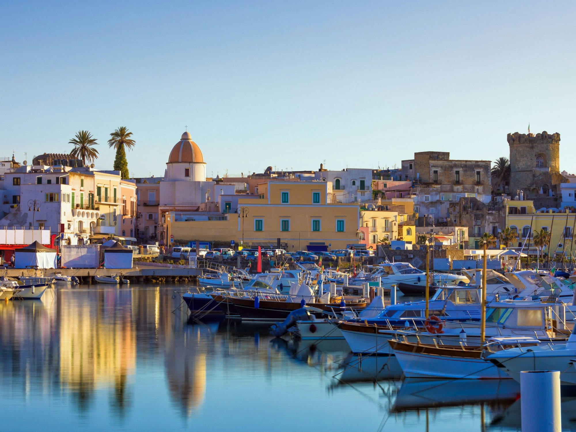 Der Hafen der Stadt Forio auf der italienischen Insel Ischia. Im Vordergrund sind einige ankernde Boote zu sehen, im Hintergrund die bunten Häuser der Stadt.