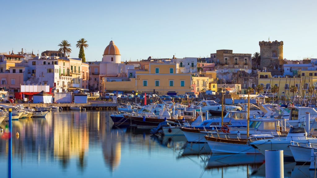 Der Hafen der Stadt Forio auf der italienischen Insel Ischia. Im Vordergrund sind einige ankernde Boote zu sehen, im Hintergrund die bunten Häuser der Stadt.