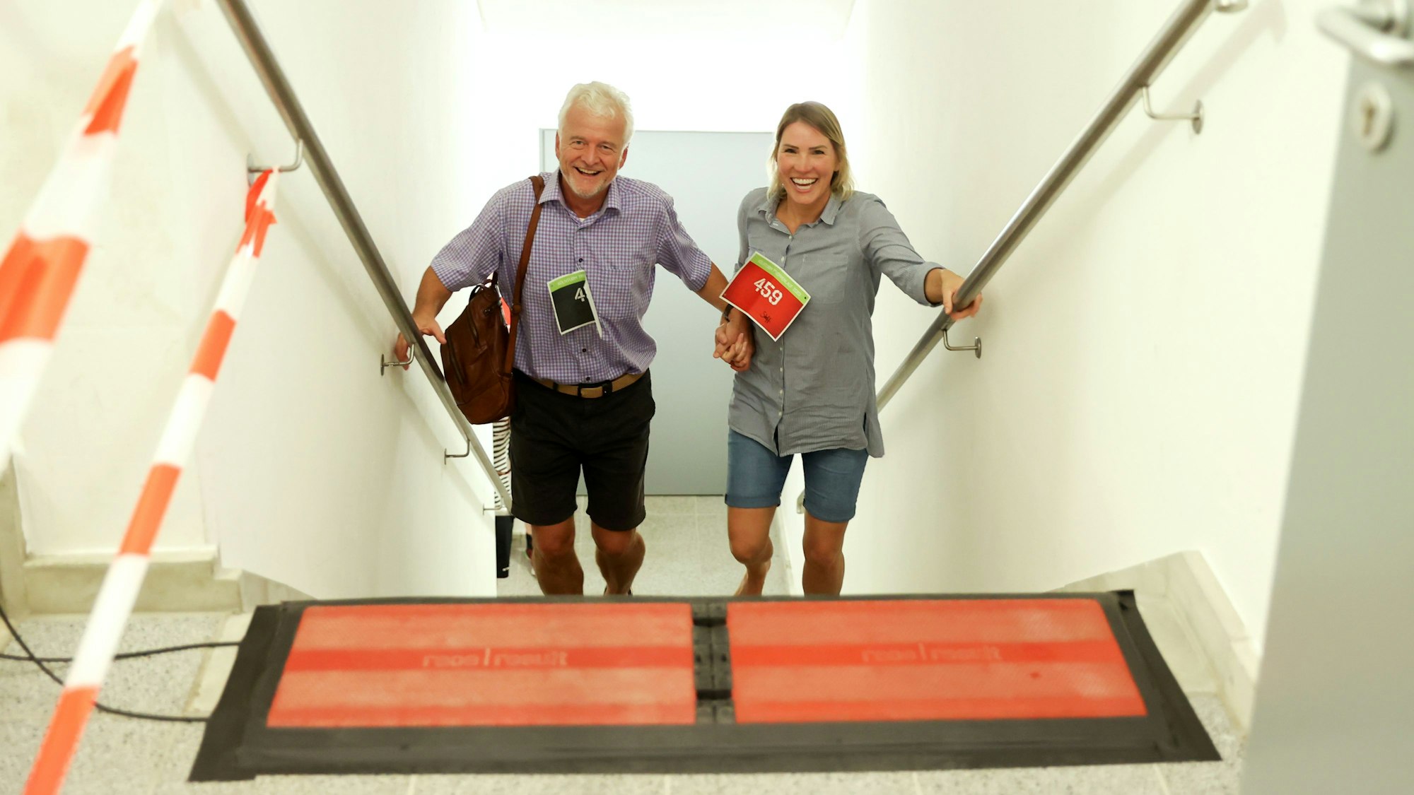 Ein Mann und eine Frau kommen lachend und händchenhaltend eine Treppe hinauf.
