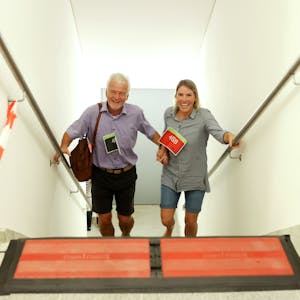 Ein Mann und eine Frau kommen lachend und händchenhaltend eine Treppe hinauf.