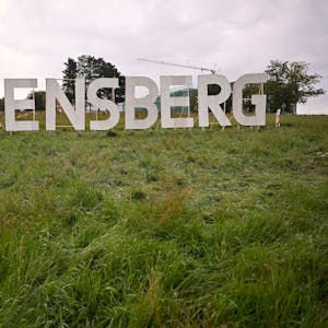 Das Foto zeigt die Kunstinstallation „Bensberg“: Weiße Buchstaben wie die des Hollywood-Schriftzugs auf einer grünen Wiese.