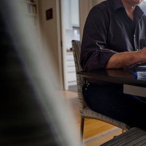 Ein Mann sitzt zuhause an einem Esstisch und arbeitet an einem Laptop.&nbsp;
