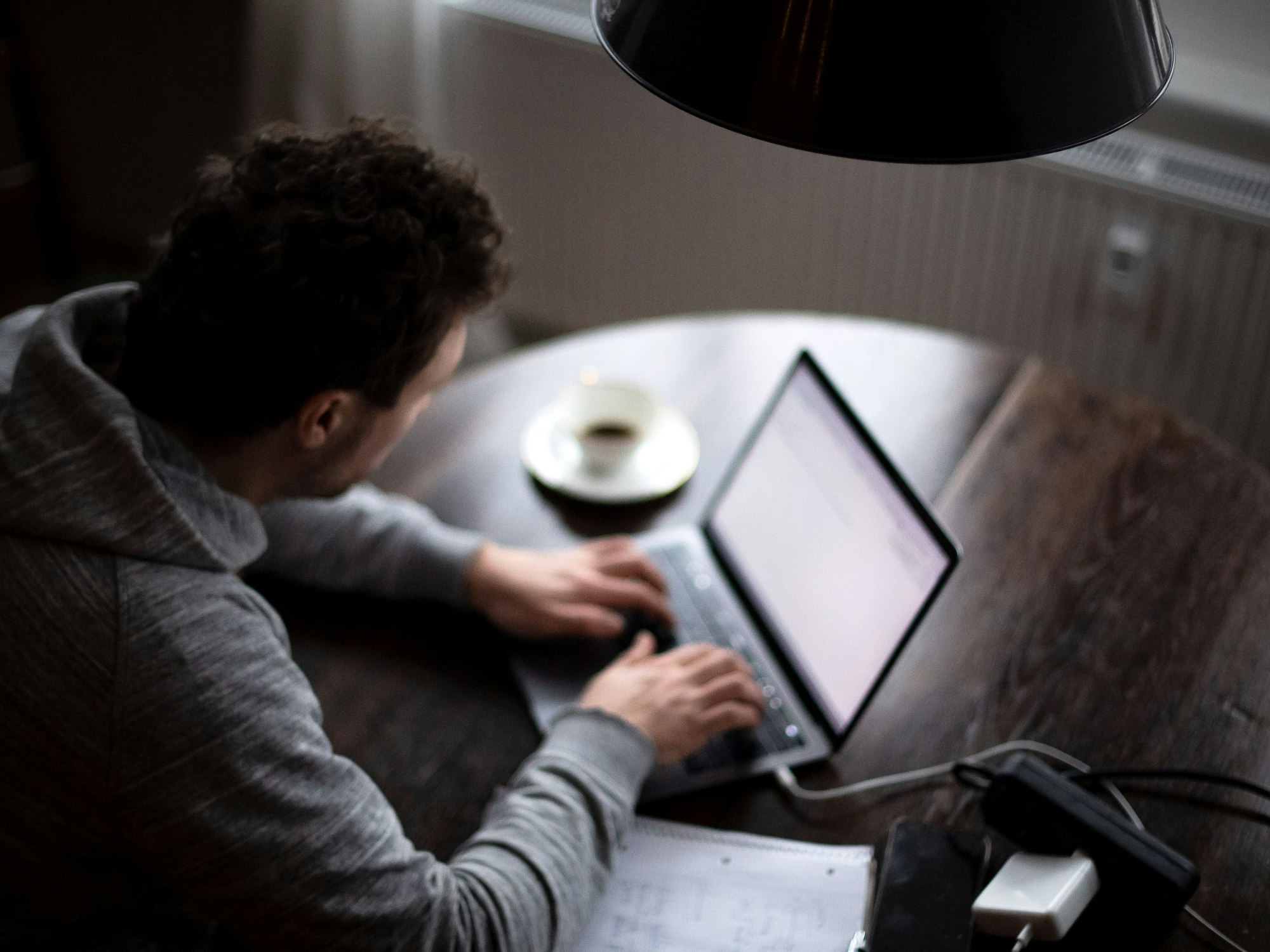 Ein Mann sitzt im Homeoffice am Tisch an einem Laptop und arbeitet (gestellte Szene).