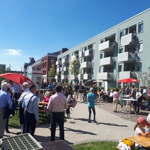 Mehrere Menschen stehen vor dem neuen Wohnhaus an der Ecke Josefine-Clouth-Straße/Xantener Straße.