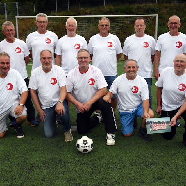 Eine Fußballmannschaft, bestehend aus alten Herren, posiert zum Mannschaftsfoto auf einem Rasenplatz.&nbsp;