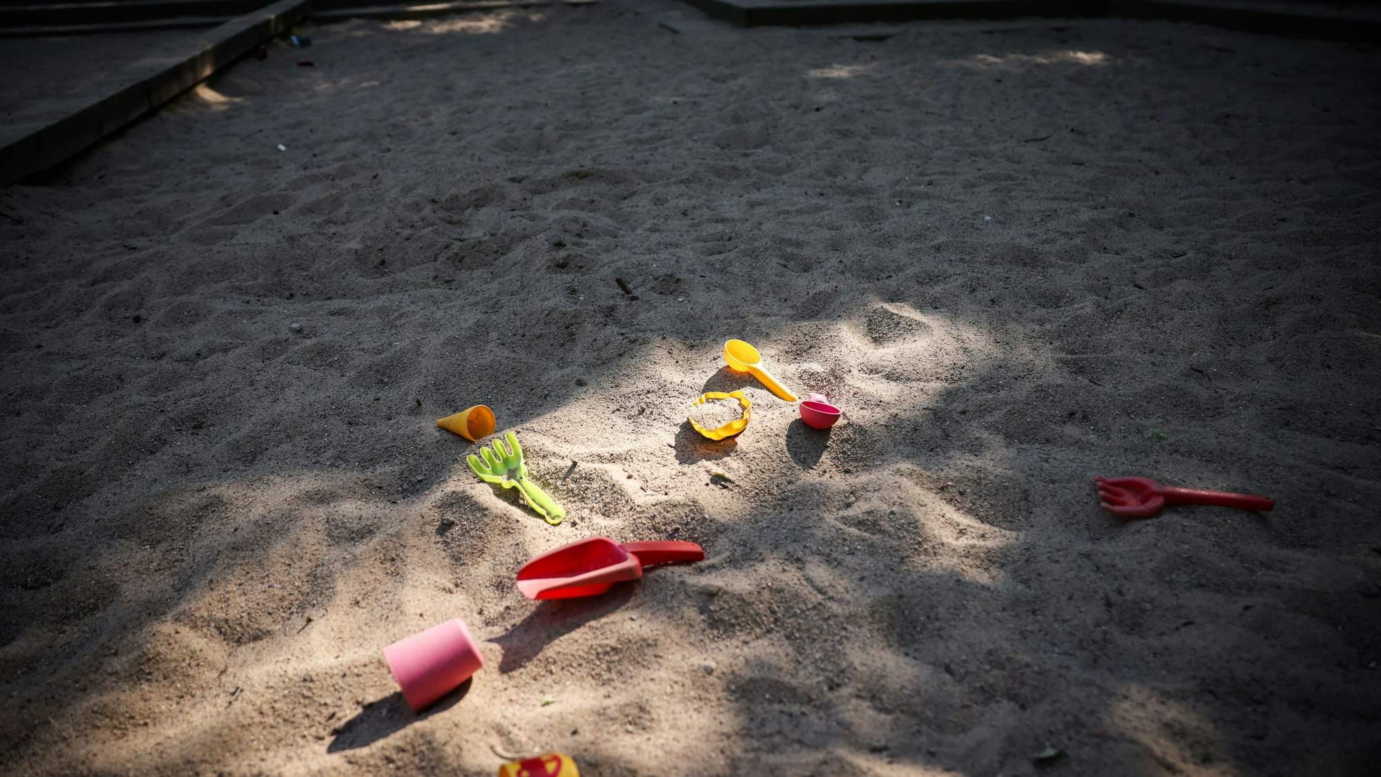 Spielzeug liegt in einer Sandkiste auf einem Spielplatz als Symbol dafür, dass in der Stadt 500 Kita-Plätze fehlen.
