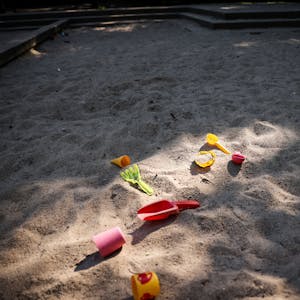 Spielzeug liegt in einer Sandkiste auf einem Spielplatz als Symbol dafür, dass in der Stadt 500 Kita-Plätze fehlen.&nbsp;