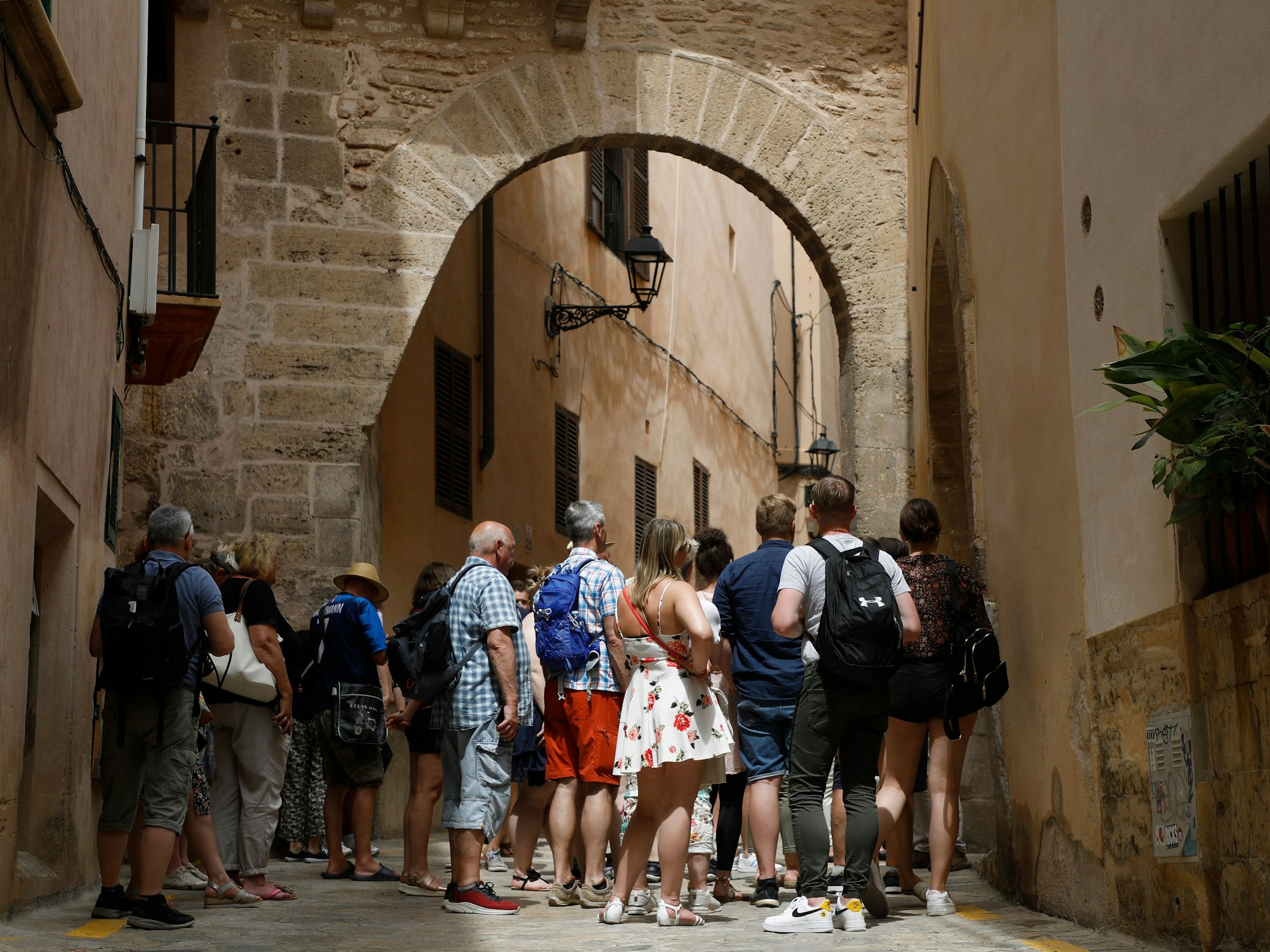 Touristen und Touristinnen stehen bei einer geführten Tour in einer Gasse in Palma de Mallorca, hier im Juni 2022.