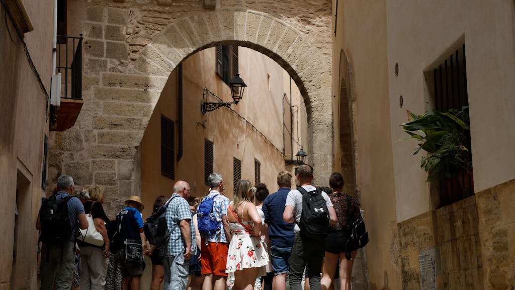 Touristen und Touristinnen stehen bei einer geführten Tour in einer Gasse in Palma de Mallorca, hier im Juni 2022.