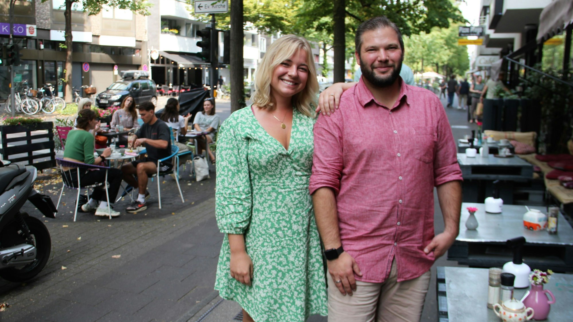Carina Birnbacher und Michael Spernat vom Ring Lindenthaler Geschäftsleute stehen auf zwischen den Tischen eines Straßencafés auf der Dürener Straße.