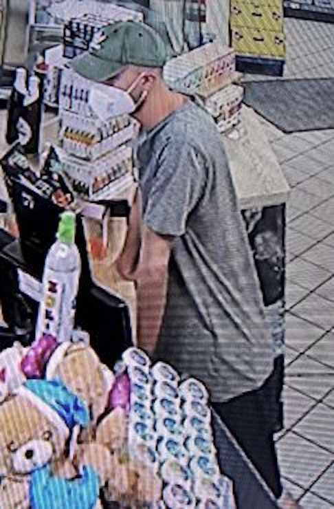 Bild aus Überwachungskamera zeigt einen Mann mit Maske, der an einer Tankstellenkasse steht.