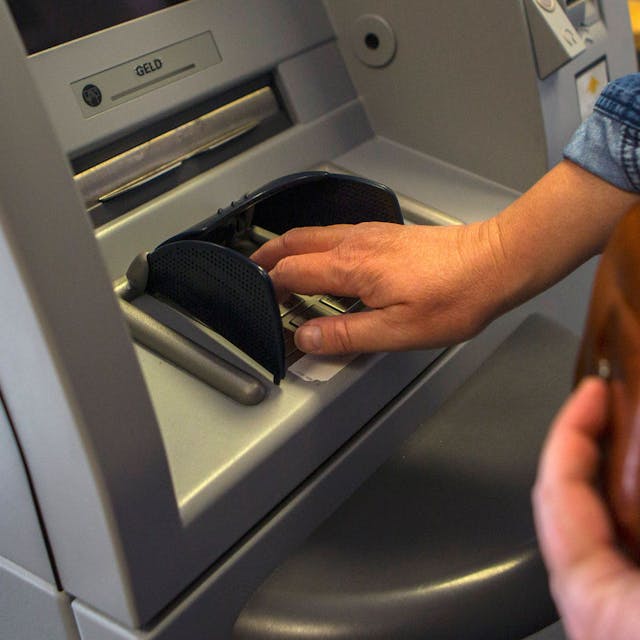 Eine Person gibt ihre PIN-Nummer beim Geldabheben an einem Geldautomaten ein.&nbsp;