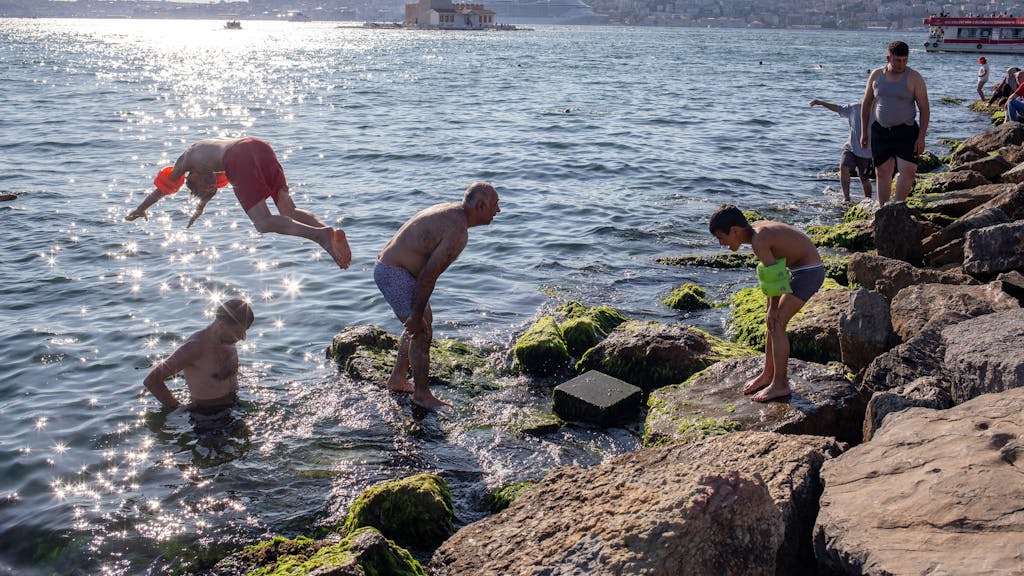 Menschen springen am Bosporus ins Meer, um sich abzukühlen.