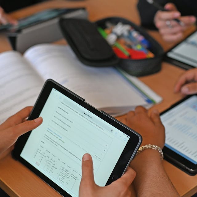 Kinder sitzen in einer Klasse und arbeiten mit ihren Tablets.