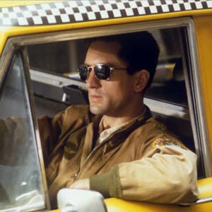 Ein Mann mit Sonnenbrille sitzt am Steuer eines Taxis.&nbsp;