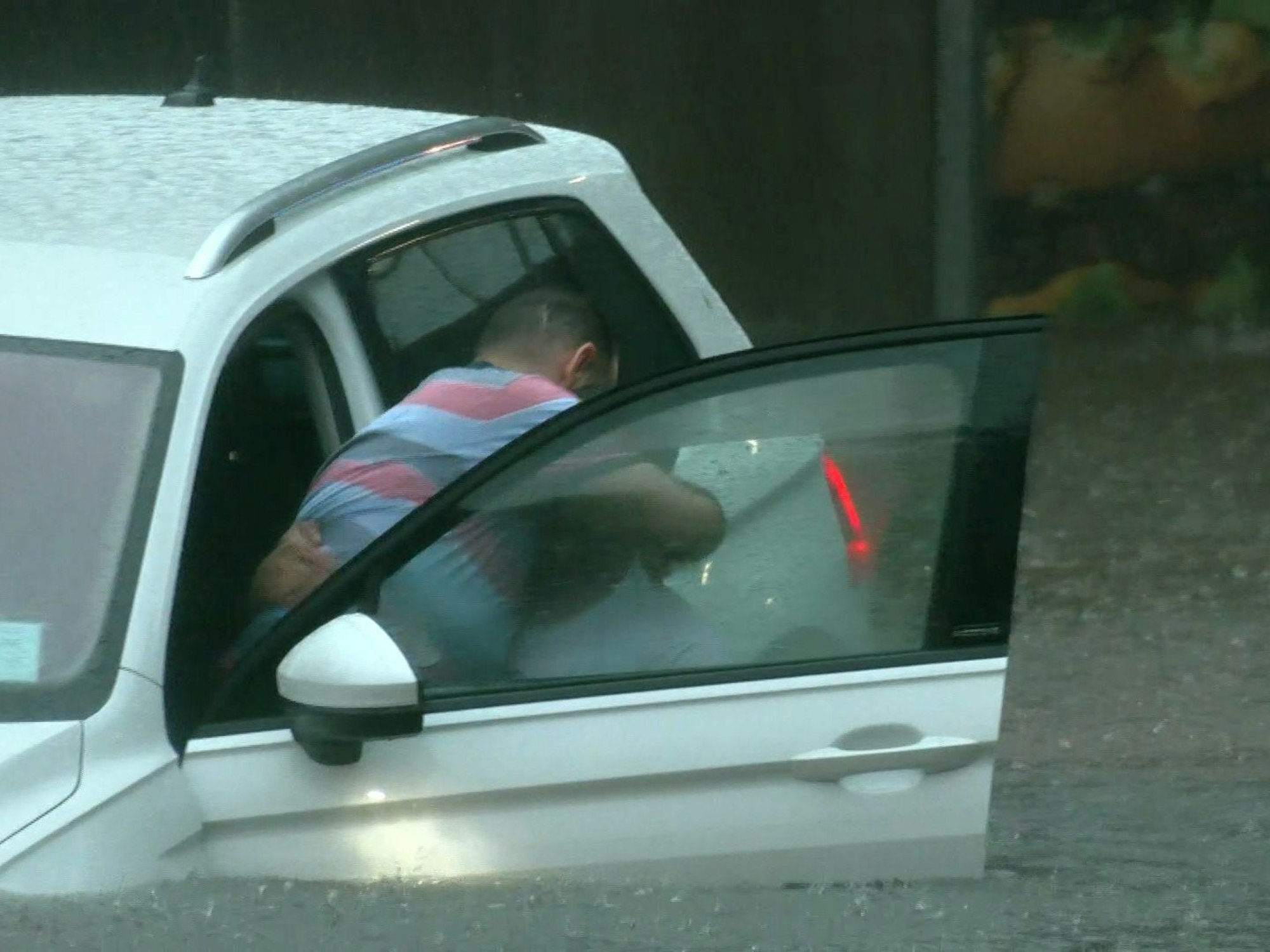 Einer Person wird aus dem Auto bei einer überschwemmten Unterführung geholfen.
