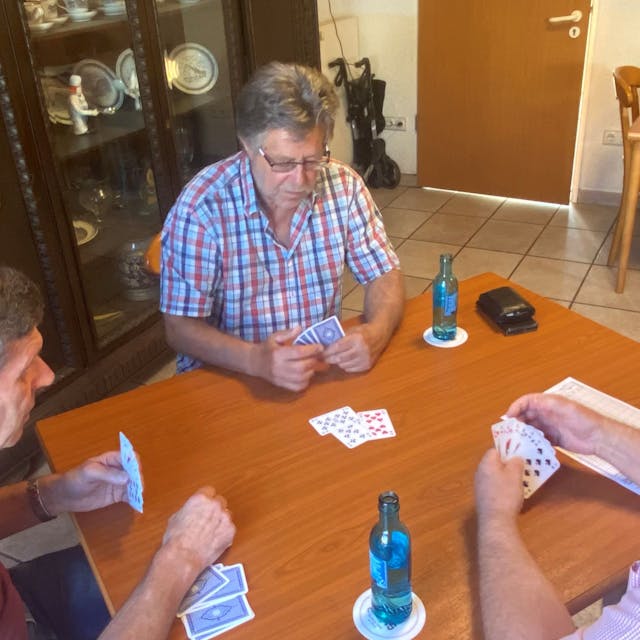 Herbert Lehmann, Peter Metzner und Hubert Siminski sitzen am Tisch und spielen Skat.