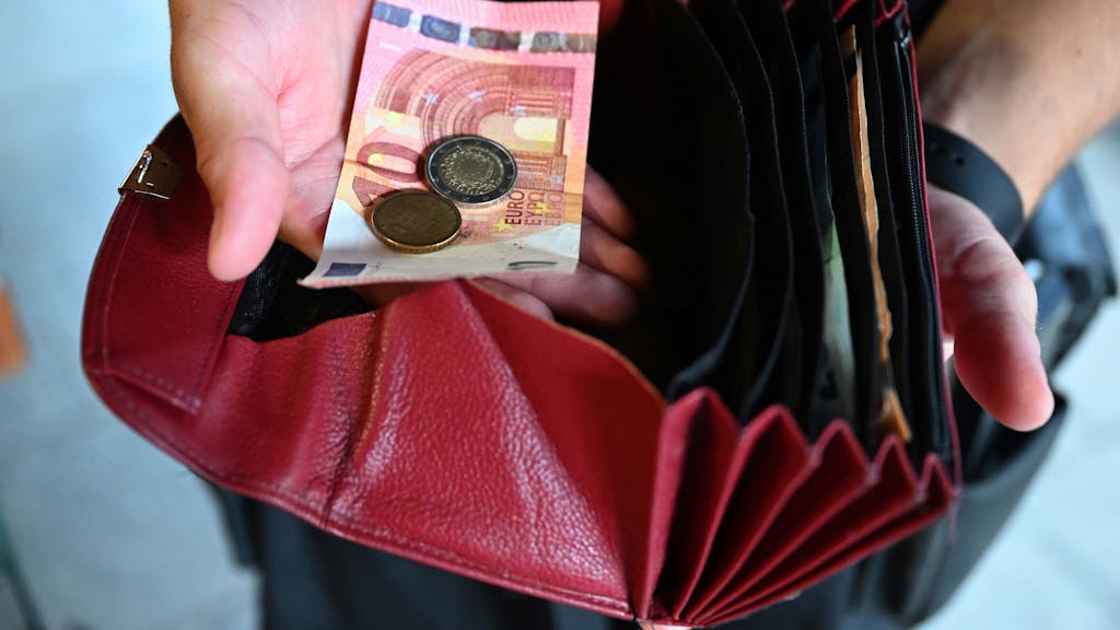 Ein Kellner mit rotem Portemonnaie und Bargeld.