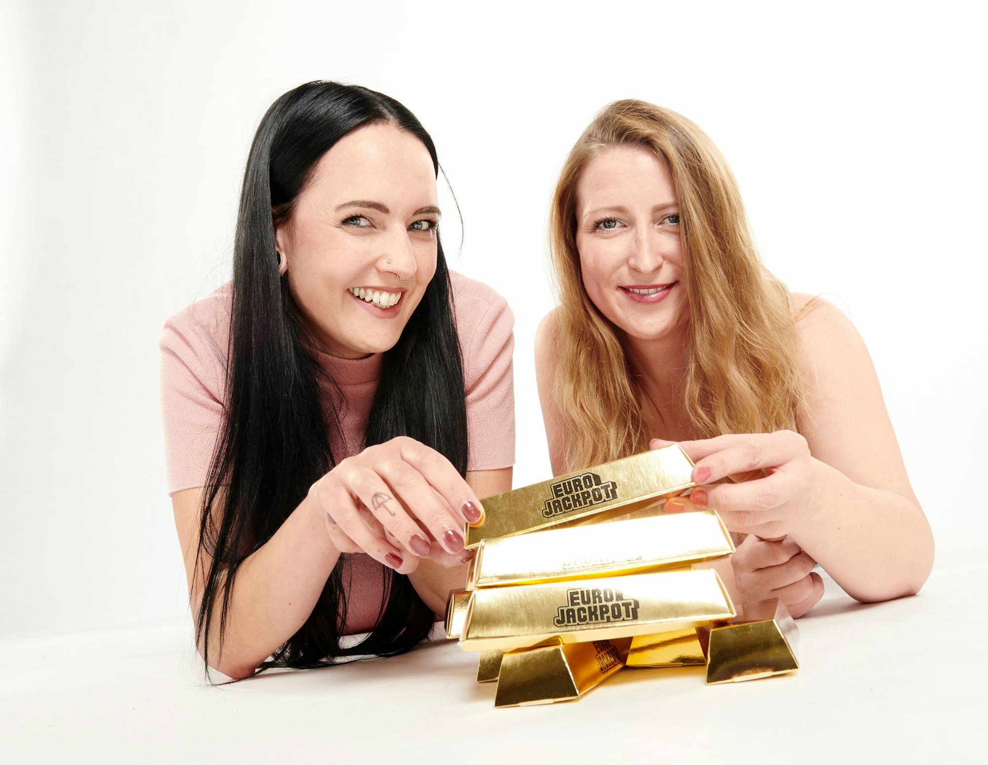 Zwei Frauen mit Eurojackpot Goldbarren in der Hand.