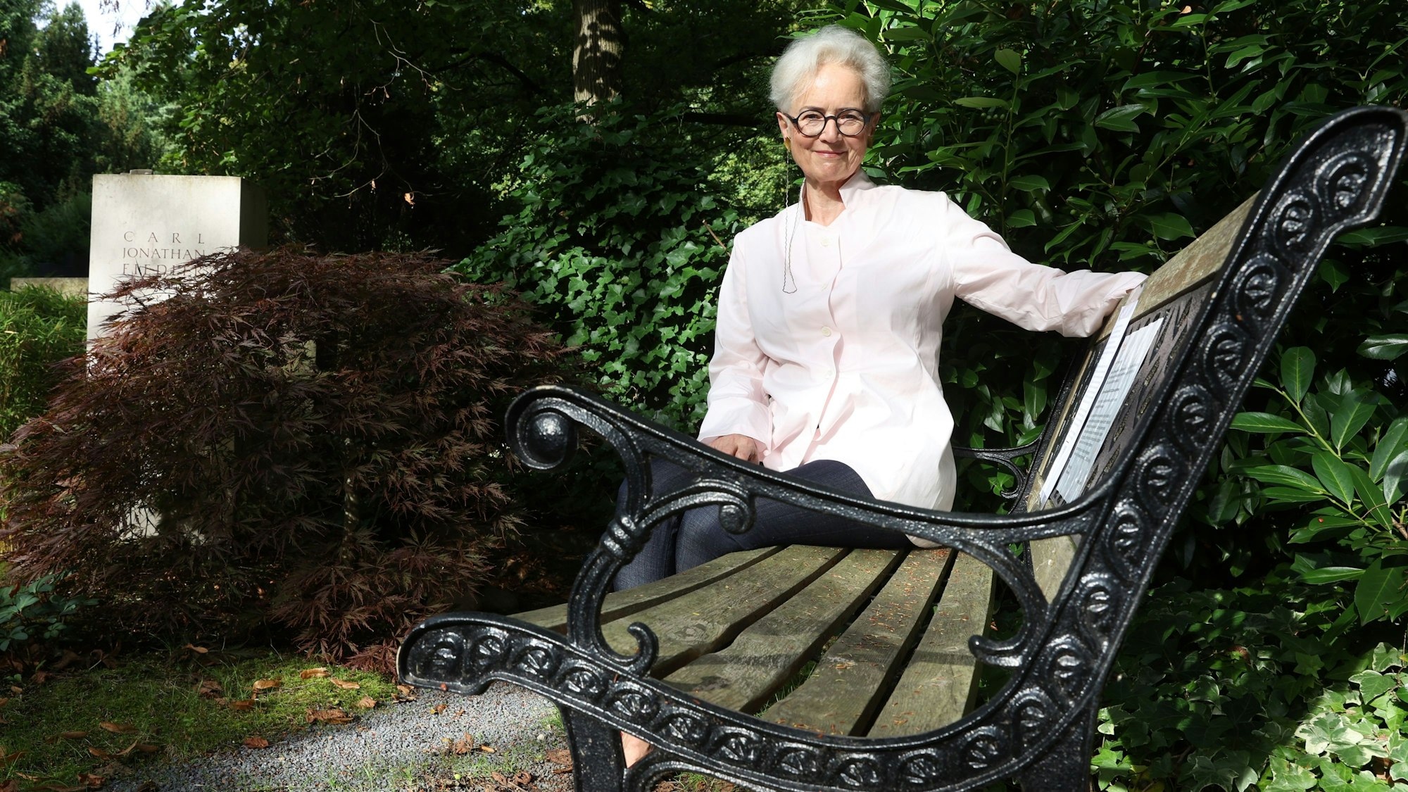 Dorothee Fiedler
sitzt auf einer Holzbank mit Metallgestell, neben dem Grab ihres Sohnes.