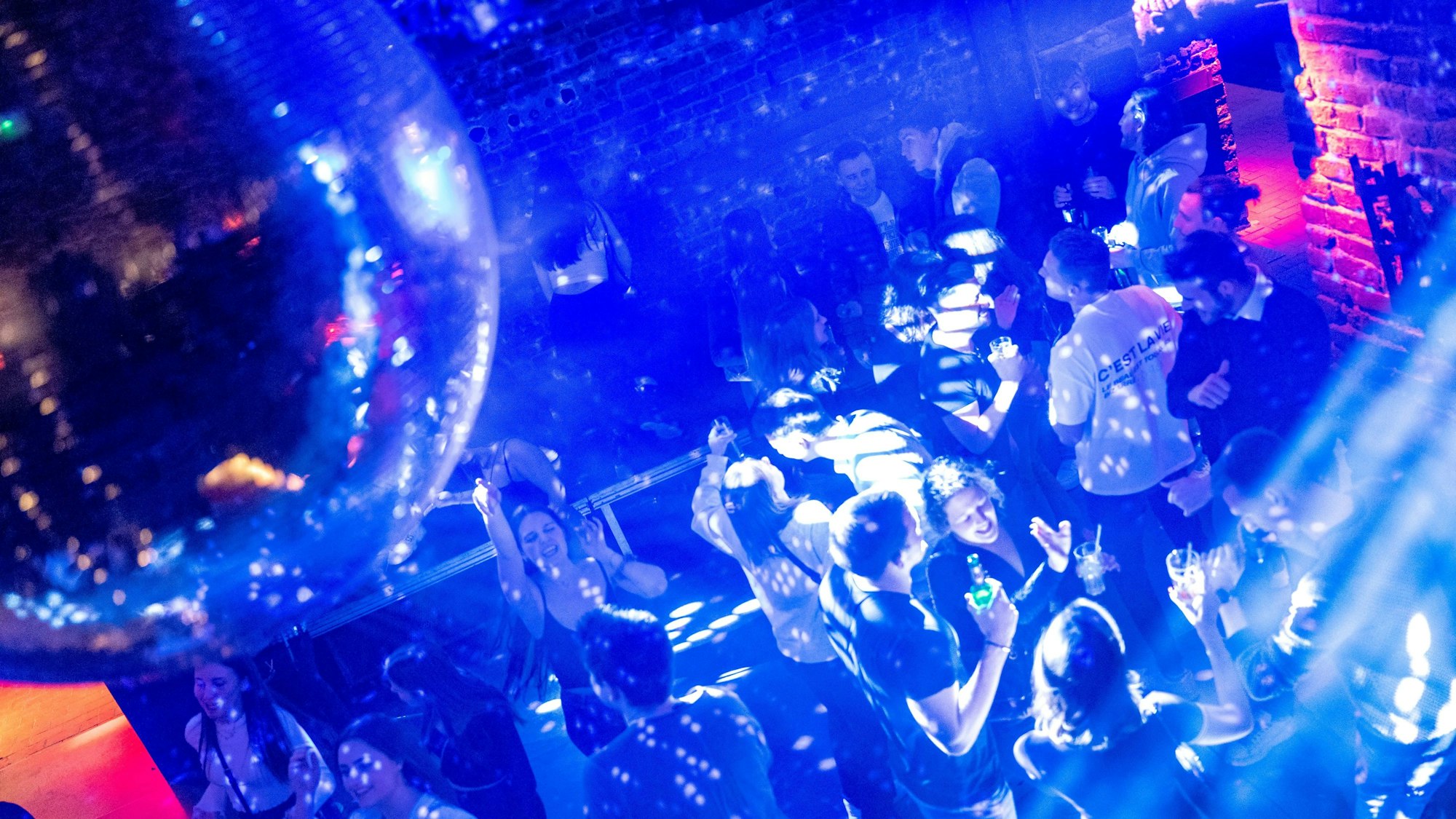Junge Leute feiern und tanzen bei Discobeleuchtung in einem Club.