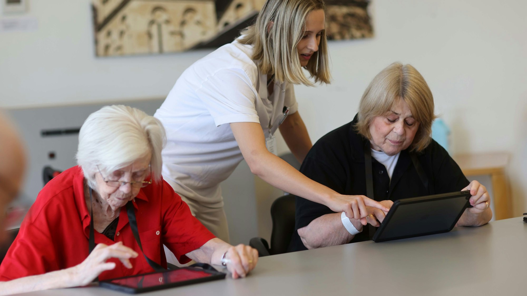 Gina Conrad zeigt zwei Seniorinnen etwas auf den Tablets