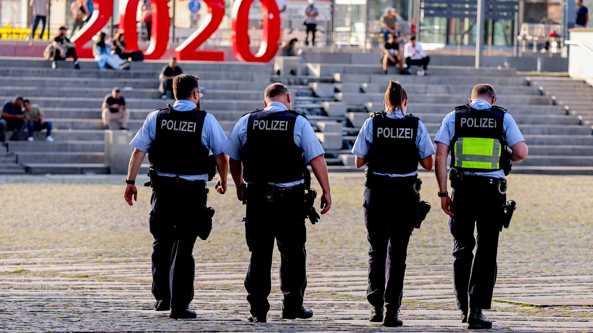 Vier Polizistinnen und Polizisten laufen über den Wiener Platz in Köln.