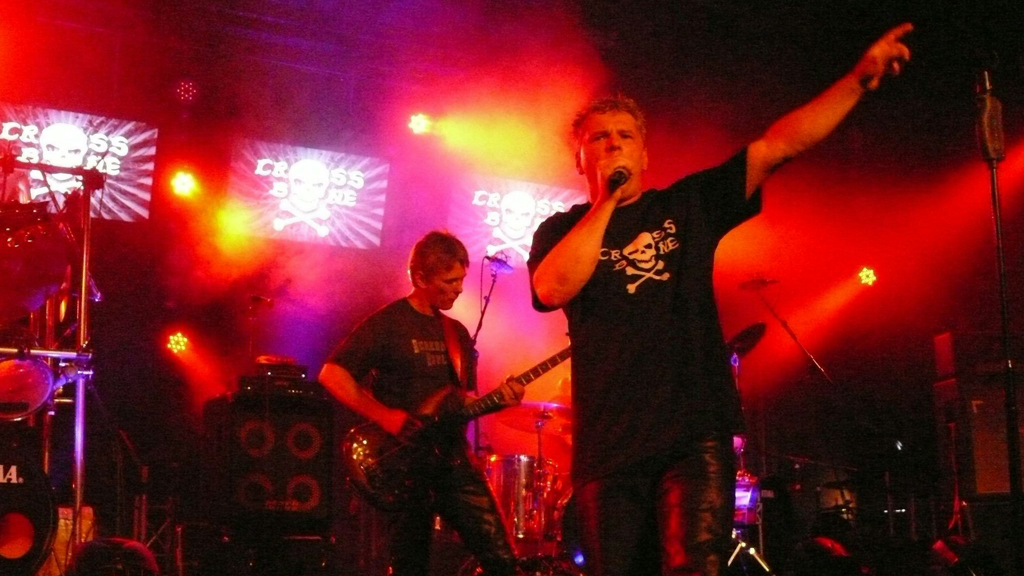 Rockmusiker spielen auf einer rot ausgeleuchteten Bühne.