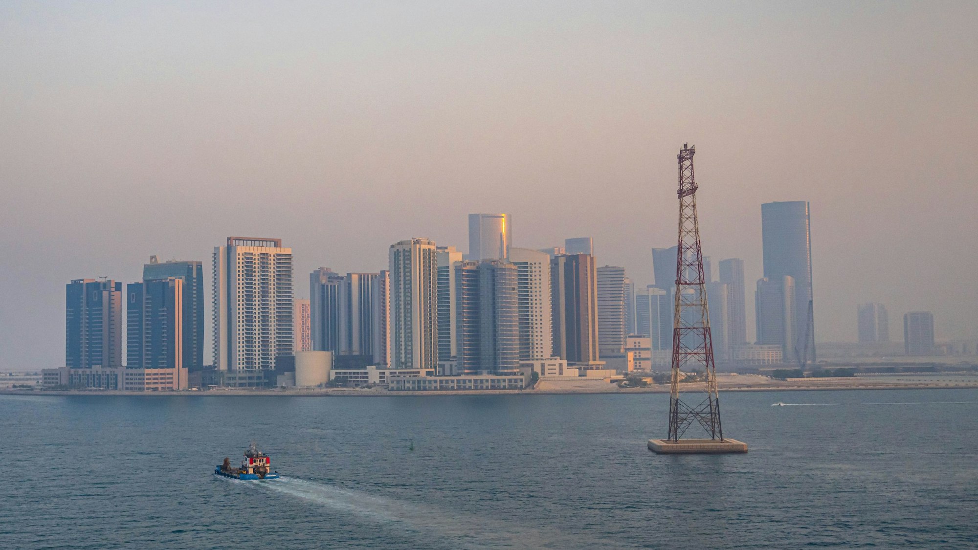 Blick vom Meer auf die Skyline von Abu Dhabi mit vielen Wolkenkratzern.
