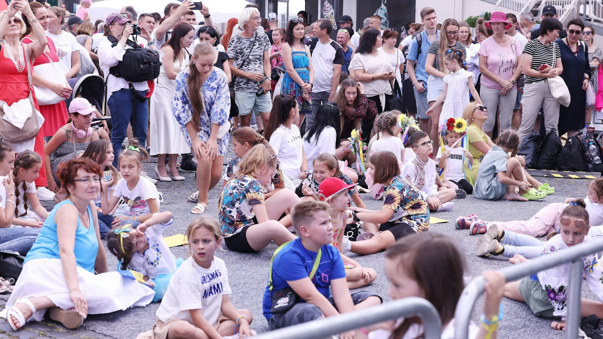 Zuschauer verfolgen beim Ukraine-Tag am Rheinufer in Köln eine Aufführung auf der Bühne.