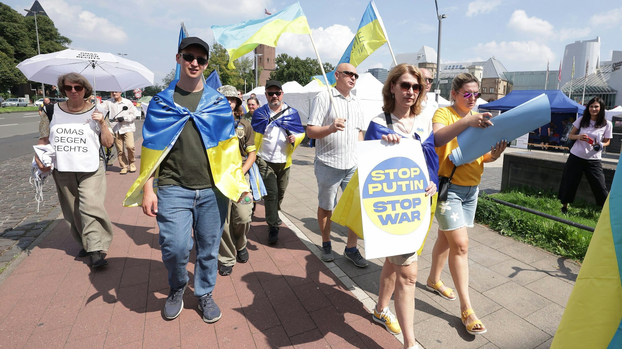 Menschen demonstrieren gegen den russischen Angriffskrieg. Zum zweiten Mal findet der Ukraine-Tag mit einem Benefizfestival für ukrainische Kunst und Kultur am Rheinufer in Köln statt.