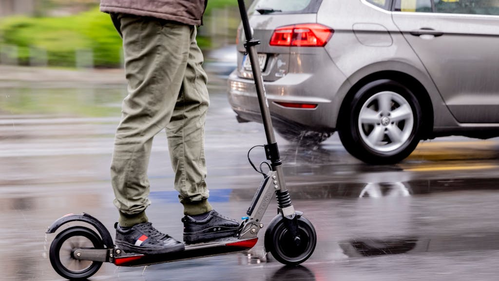 Ein Mann fährt mit einem E-Roller auf der Straße.