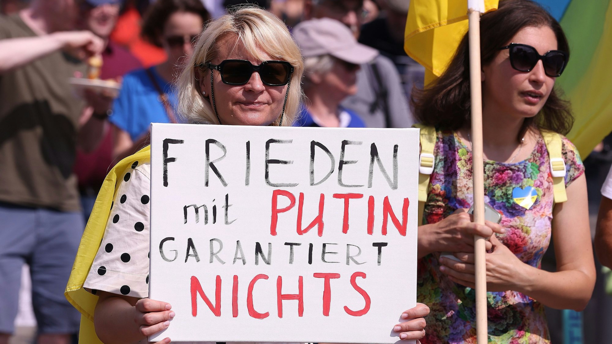 Eine Frau hält ein Schild bei der Demonstration gegen den russischen Angriffskrieg vor den Körper.