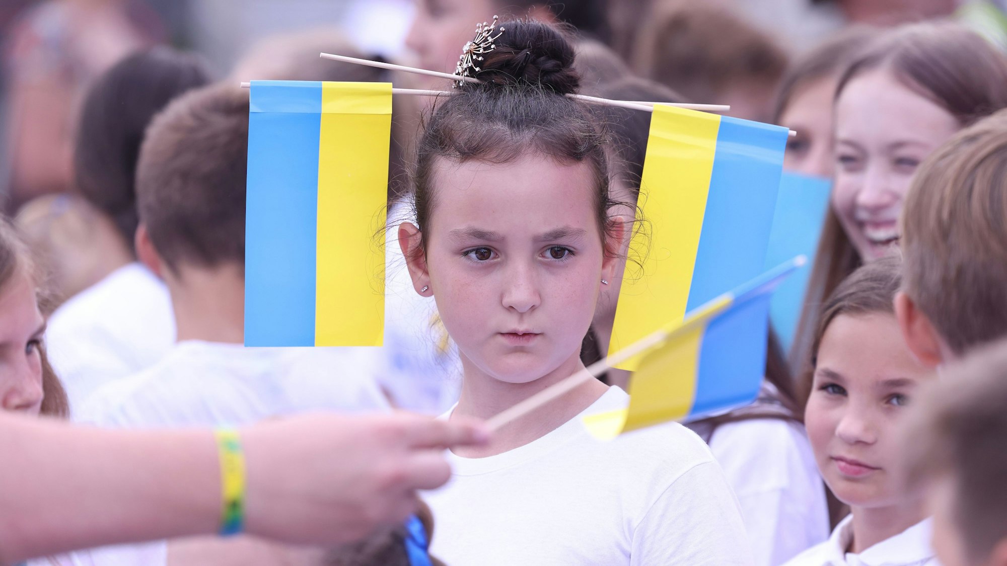 Ein Mädchen hat zwei ukrainische Flaggen in ihren Haaren.