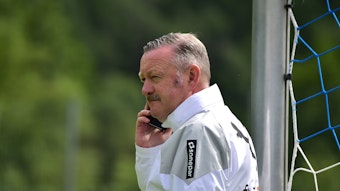 Roland Virkus hält im Trainingslager von Borussia Mönchengladbach am 27. Juli 2023 ein Handy am Ohr.