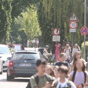 Autos und Schulkinder in einer schmalen Straße
