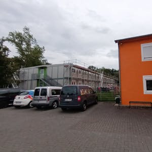 Eingerüstete Container neben einem Wohn- und Bürogebäude.