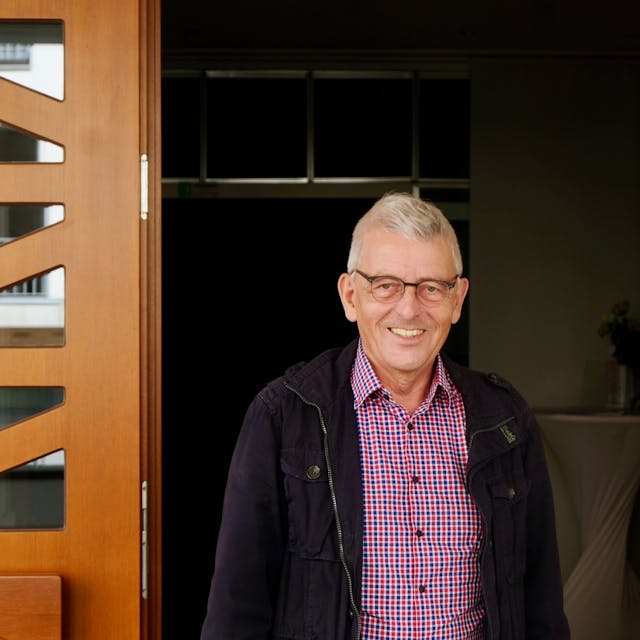 Ein Mann mit kurzem grauen Haar und Brille steht in einer geöffneten Kirchentür.