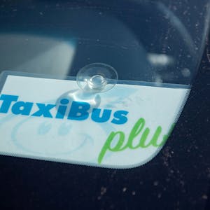 Das Bild zeigt ein Schild in einem Taxi, das kenntlich macht, dass es sich um einen TaxiBus handelt.