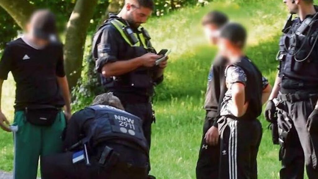 Polizisten durchsuchen drei Kinder von Kopf bis Fuß im Mülheimer Stadtpark.