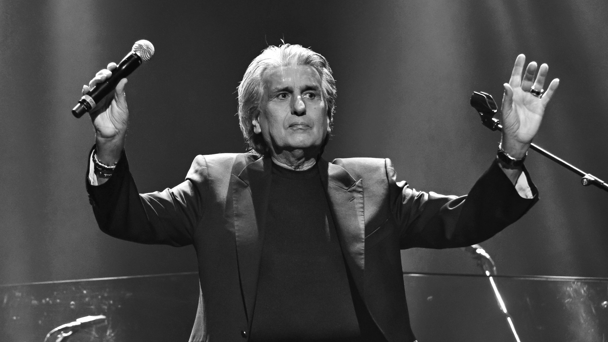 Schwarzweißbild von Toto Cutogno, italienischer Sänger, der bei einem Konzert auf der Bühne steht.