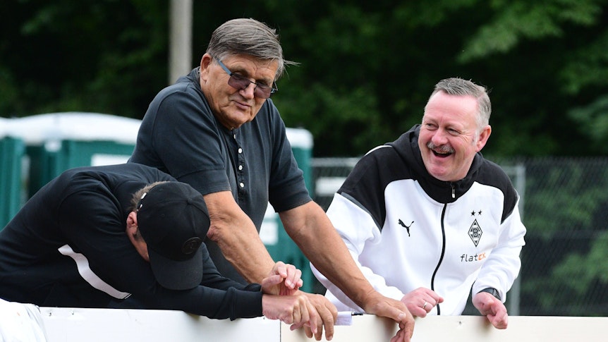 Roland Virkus (r.) bringt Präsidiumsmitglied Hans Meyer (M.) und Stadionsprecher Torsten Knippertz im Trainingslager von Borussia Mönchengladbach am 25. Juli 2023 zum Lachen.