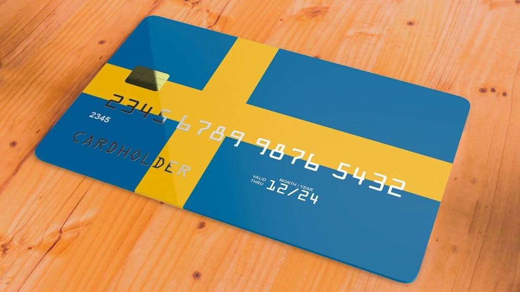 Eine Kreditkarte mit Schwedenflagge liegt auf einem Tisch.