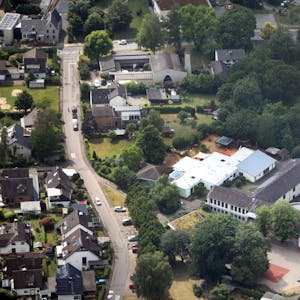 Auf einem Luftbild sind eine Kirche, Häuser, Gärten und Bäume zu sehen.