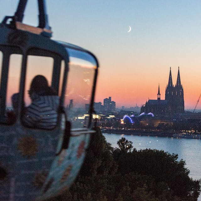 Eine Gondel der Kölner Seilbahn im Abendlicht mit Blick auf den Kölner Dom.





