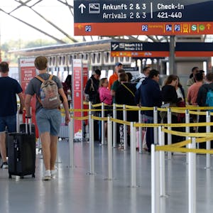Reisende gehen im Flughafen Köln/Bonn durch die Abflughalle.