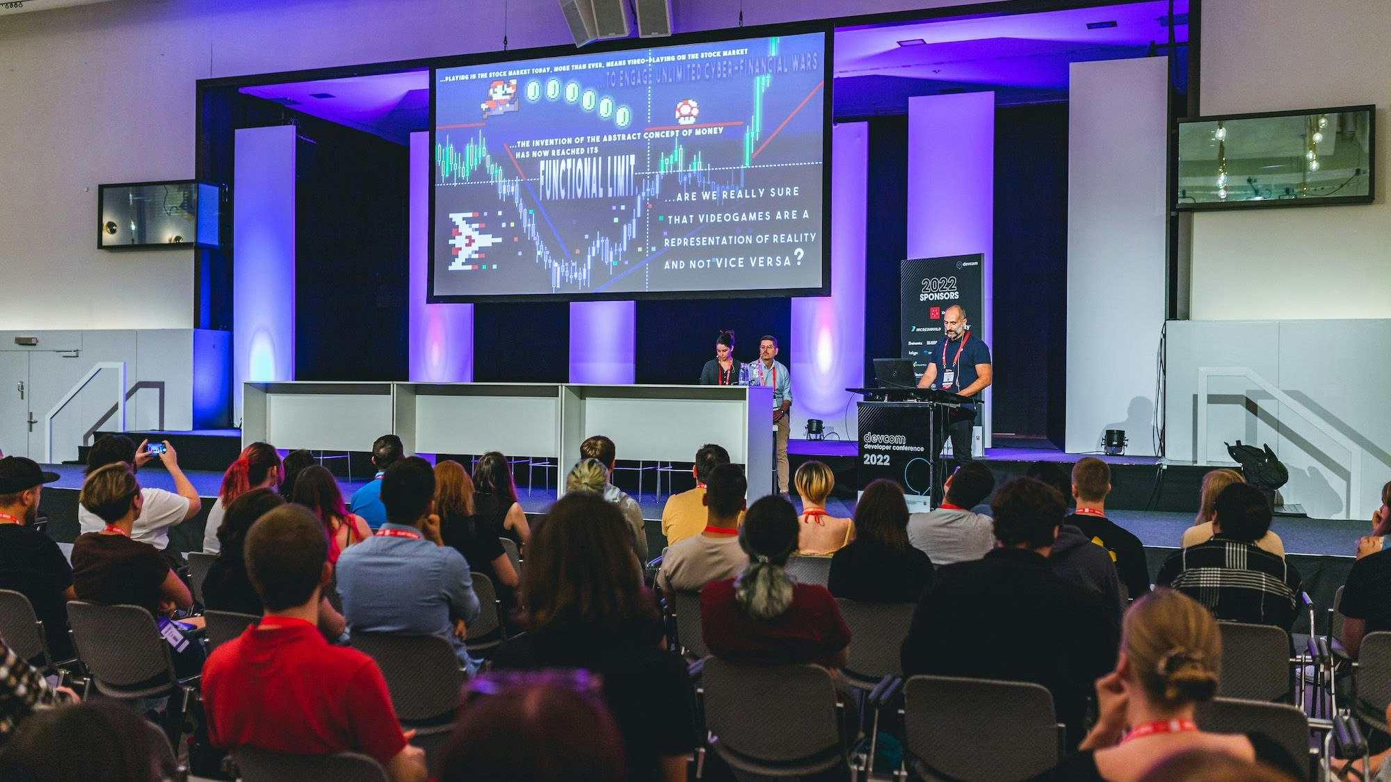 Devcom Developer Conference 2022: Zuschauer auf Stühlen wohnen einer Präsentation bei.