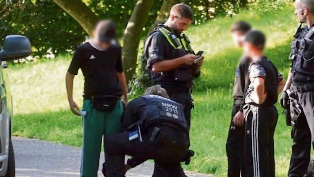 Polizisten durchsuchen drei Kinder von Kopf bis Fuß im Mülheimer Stadtpark-