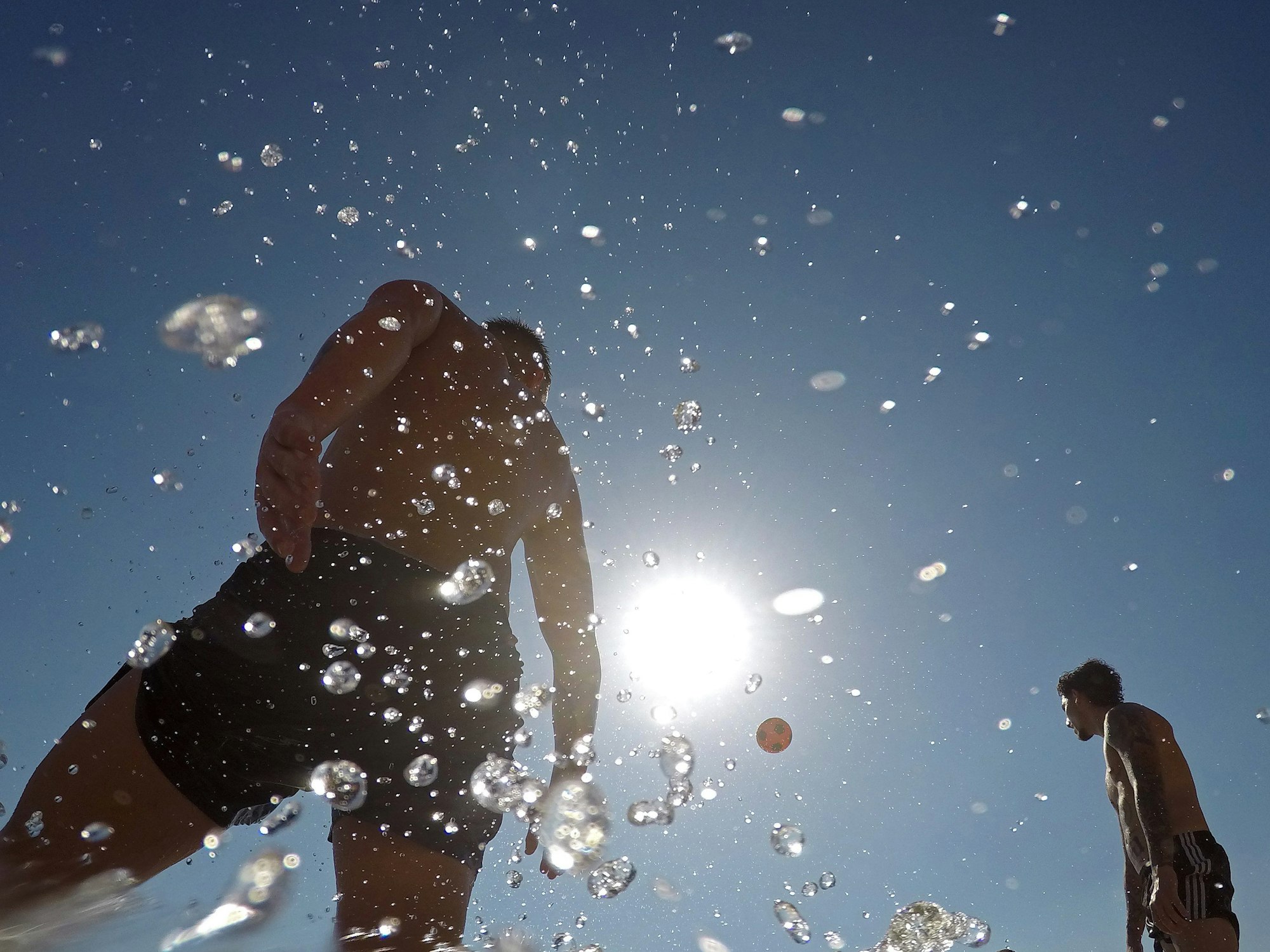 Menschen spielen mit einem Ball am Meer an einem warmen Sommertag am Strand Cala Major auf Mallorca.