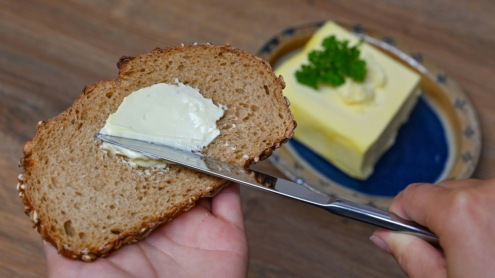 Eine Person streicht Butter auf eine Scheibe Brot. Symbolbild für Brot-Rückruf.